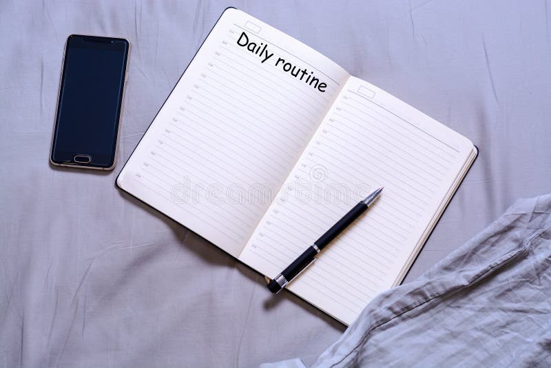 Abra o bloco de notas com a pena preta com a inscrição e o lugar para mentiras do texto na cama com um smartphone O conceito de f imagem de stock Abra o bloco de notas com a pena preta com a inscrição e o lugar para mentiras do texto na cama com um smartphone O conceito de f imagem de stock