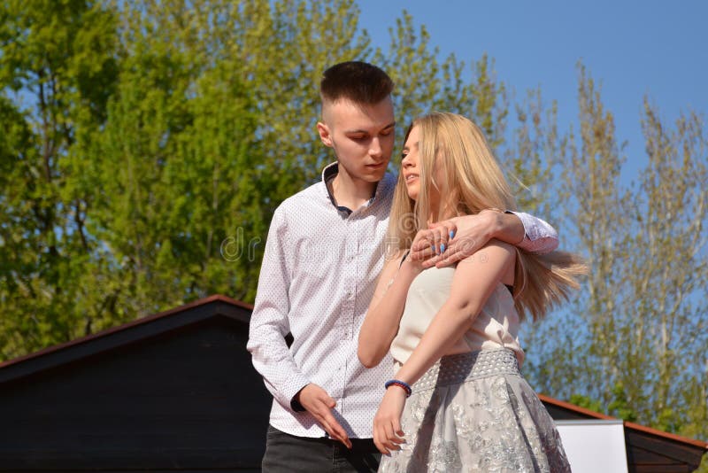Abrazan a la muchacha rubia joven y al hombre en día de primavera soleado en parque con el árbol verde en fondo Ci?rrese para arr fotos de archivo libres de regalías Abrazan a la muchacha rubia joven y al hombre en día de primavera soleado en parque con el árbol verde en fondo Ci?rrese para arr fotos de archivo libres de regalías