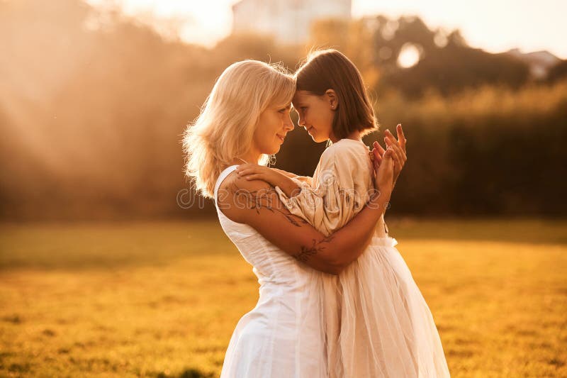 Abrazándose entre sí. la mujer con su hija está en el campo de verano imagenes de archivo