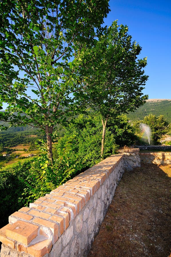 Abruzzo landscape in central Italy, with an old ruined wall, some trees and a fountain