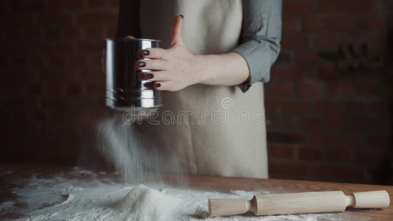 Abschluss den Frauenbäckereichef, der Mehl vom Sieb auf dem Tisch bereit für die Herstellung von hausgemachten Brot siebt. Zeitlup