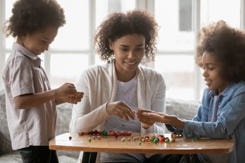 Abschluss die Afroamerikanermutter und Kinder, die mit Perlen spielen stockbilder