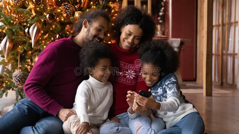 Abschluss die glückliche Afroamerikanerfamilie Smartphonewinterurlaube verwendet, die lizenzfreies stockbild