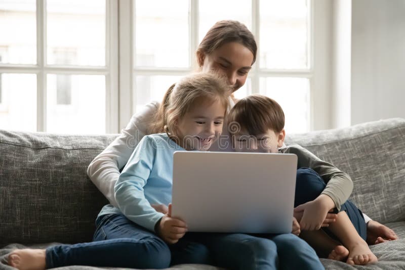 Abschluss die Mutter und zwei Kinder, die Spaß Notebook haben lizenzfreie stockfotos