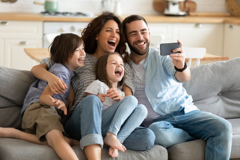 Abschluss in glückliche Eltern mit kleinen Kindern mithilfe des Smartphone zusammen. lizenzfreies stockfoto