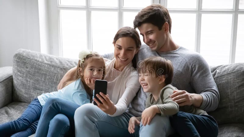 Abschluss in glückliche Eltern mit zwei Kindern unter Verwendung des Smartphone lizenzfreie stockbilder