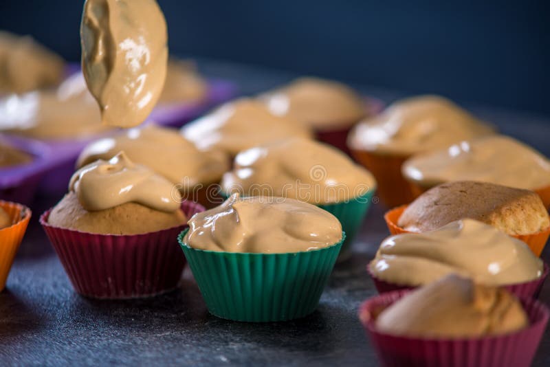 Abschluss herauf Chefgebäck gießt Creme auf frisch zubereiteten kleinen Kuchen auf dunklem Hintergrund Konzept des Süßigkeitenkoc stockbilder Abschluss herauf Chefgebäck gießt Creme auf frisch zubereiteten kleinen Kuchen auf dunklem Hintergrund Konzept des Süßigkeitenkoc stockbilder