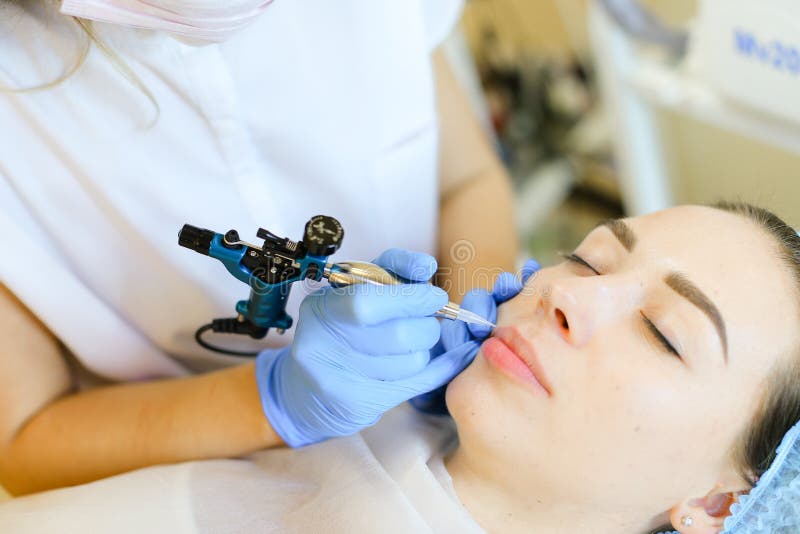 Abschluss herauf die Hand, die permanet Lippentätowierung mit microblading Gerät am Schönheitssalon macht lizenzfreie stockfotografie Abschluss herauf die Hand, die permanet Lippentätowierung mit microblading Gerät am Schönheitssalon macht lizenzfreie stockfotografie