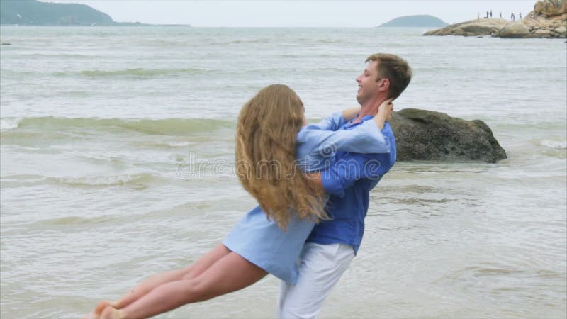 Abschluss herauf Mann kreist ein Mädchen in seinen Armen auf einem Seesandigen Strand ein Ein Paar des Liebhaberstrudels in der Z