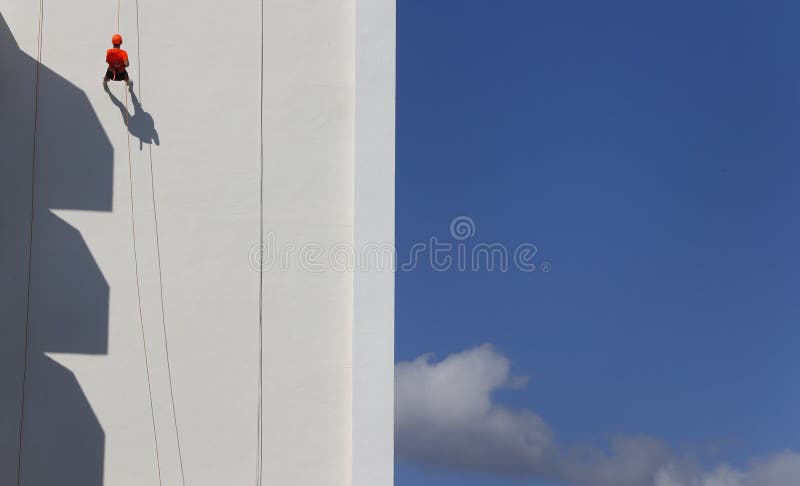 Abseil på en byggande fasad i bred sikt för palma. Abseiling på en byggande façade som delen av en lokal extrem sporthändelse i den spanska ön av Mallorca En abseil eller kallade en rapel eller rappel också är en kontrollerad nedstigning av en vertikal droppe, liksom vaggar framsidan, genom att använda ett rep