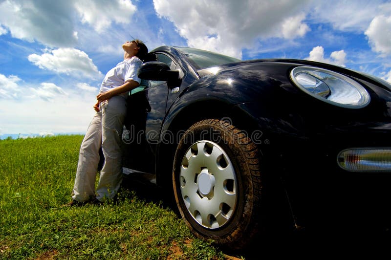 A young man leans against his broken down vehicle in absolute frustration. A young man leans against his broken down vehicle in absolute frustration