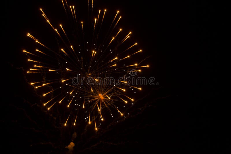 The overlap of several orange, yellow and white exploding fireworks, gives the appearance of a spider crawling up its web in the black night sky. Overlapping exploding fireworks stock images, royalty-free photos and pictures
