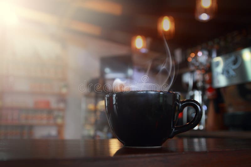 Abstract blur hot black coffee in coffee shop with wooden table.