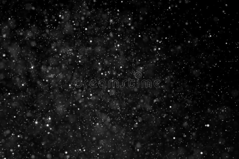 Abstract dust particles flowing on dark background with light sp stock image