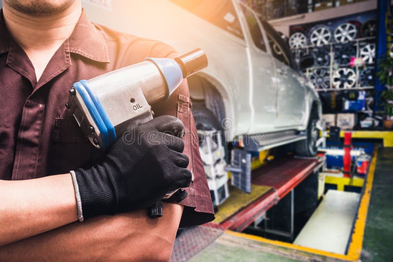 The abstract image of the technician holds an air wrench and blurred wheel alignment machine image is the backdrop. the concept of royalty free stock images