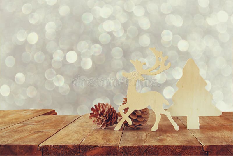 Abstract image of wooden decorative christmas tree, reindeer and pine cones on wooden table and christmas holiday bokeh lights.