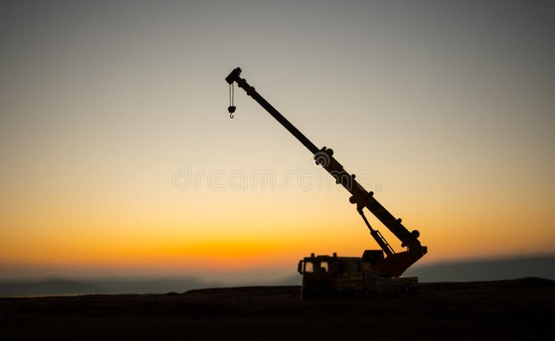 Abstract Industrial background with construction crane silhouette over amazing sunset sky. Tower crane against the evening sky.