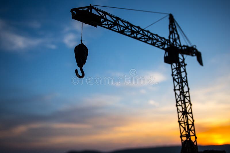 Abstract Industrial background with construction crane silhouette over amazing sunset sky. Tower crane against the evening sky.