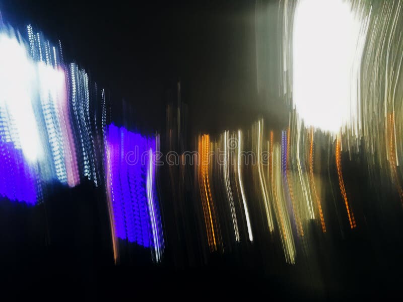 Abstract long exposure defocused photo of neon lines of city lights of phantom blue, yellow and white colors at night