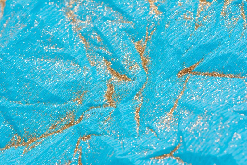 Abstract macro blue crumpled paper background with gold glitter stock photo