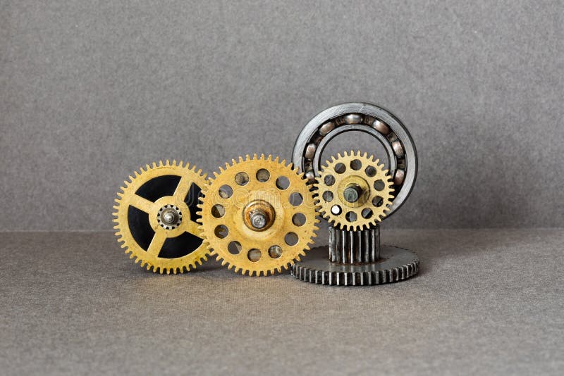 An abstract mechanical composition, installation made up of antique bearings and bronze cogs wheels gears of various. Kinds. Gray background stock photography An abstract mechanical composition, installation made up of antique bearings and bronze cogs wheels gears of various. Kinds. Gray background stock photography