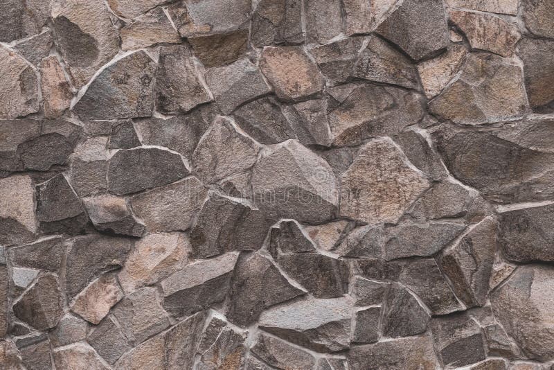 Abstract pattern of brown stone texture. Brick wall background. Rough granite surface. Cracked rock. Decorative tile on facade of stock photo