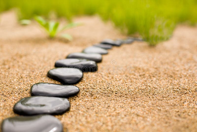 Abstract sentiero di pietre sulla sabbia, su uno sfondo di erba.