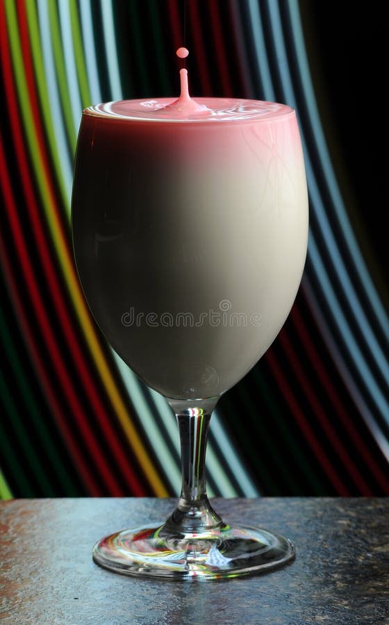 Abstract shot of a wine glass filled with milk and a splashing highspeed droplet coming out of the top. Abstract shot of a wine glass filled with milk and a splashing highspeed droplet coming out of the top.