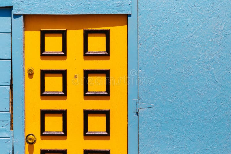 Abstract Yellow Door Design on a Sky Blue Colored Wall Stock Image
