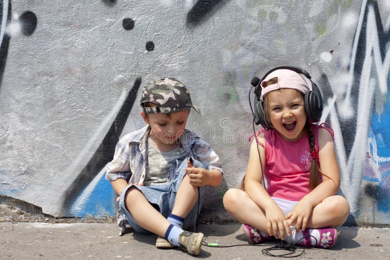 Kids listen to music abstract concept against graffiti wall in the city. Kids listen to music abstract concept against graffiti wall in the city