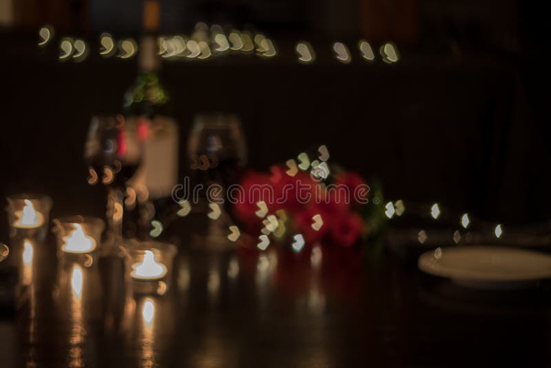 Abstract defocused background of red wine and roses on dark table for romantic dinner date night heart bokeh.  Date night, romance, restaurant, dinner,  anniversary, Valentine`s Day, celebrate. Abstract defocused background of red wine and roses on dark table for romantic dinner date night heart bokeh.  Date night, romance, restaurant, dinner,  anniversary, Valentine`s Day, celebrate.