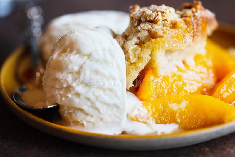 Abstract of freshly baked drop biscuit peach cobbler with melting ice cream. Selective focus with extreme blurred background. Abstract of freshly baked drop biscuit peach cobbler with melting ice cream. Selective focus with extreme blurred background