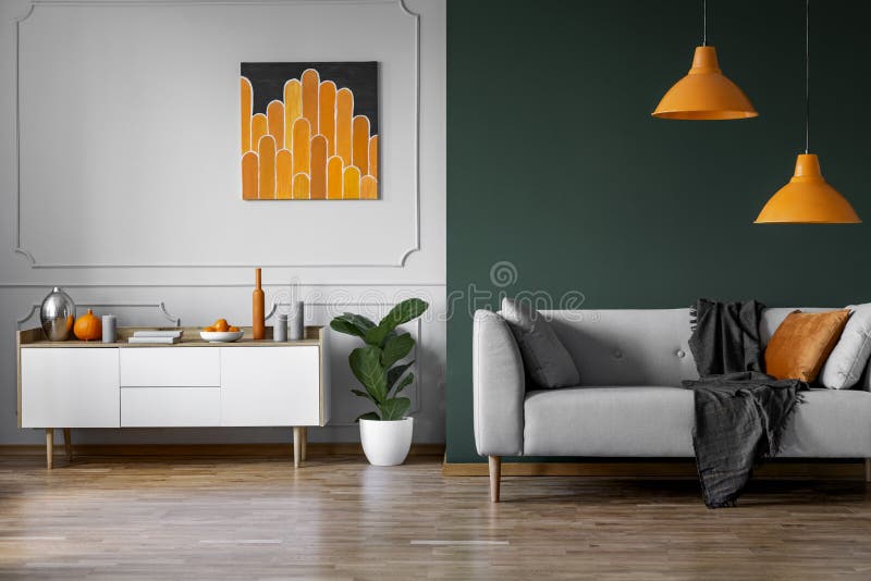 Abstrakte orange Malerei auf der grauen Wand des stilvollen Wohnzimmers Innen mit weißem Holzmöbel und grauer Couch