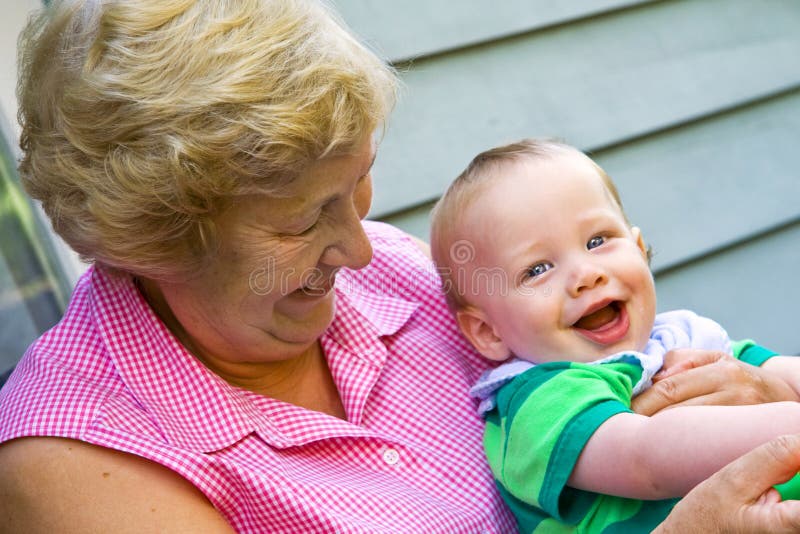 Grandmother holding happy grandson in the garden. Grandmother holding happy grandson in the garden