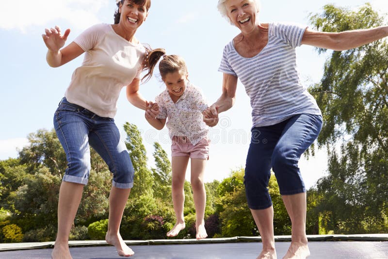 Grandmother, Granddaughter And Mother Bouncing On Trampoline. Grandmother, Granddaughter And Mother Bouncing On Trampoline