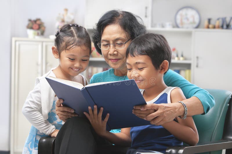 Abuela y libro de lectura de los nietos junto fotos de archivo Abuela y libro de lectura de los nietos junto fotos de archivo