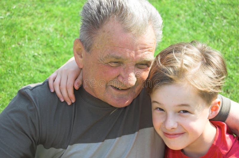 Grandfather with grandson sitting together on the grass. Grandfather with grandson sitting together on the grass