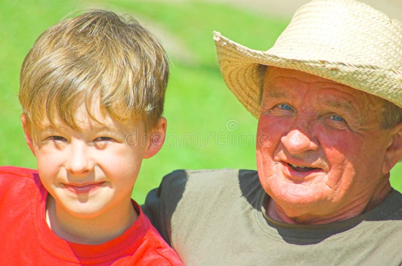 Grandfather with grandson sitting together on the grass. Grandfather with grandson sitting together on the grass