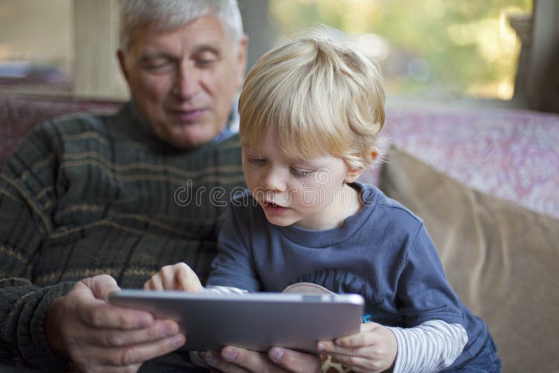 Abuelo y nieto que usa la PC de la tablilla fotografía de archivo libre de regalías Abuelo y nieto que usa la PC de la tablilla fotografía de archivo libre de regalías