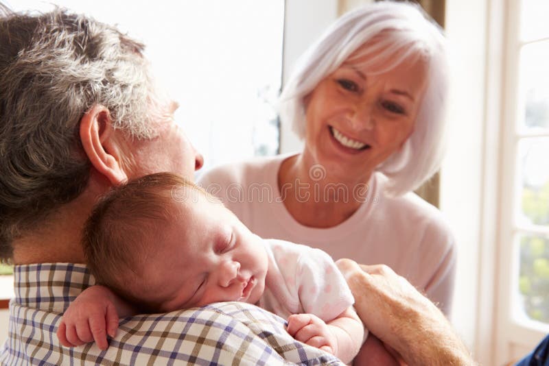 Abuelos que detienen a la nieta recién nacida durmiente del bebé imagen de archivo