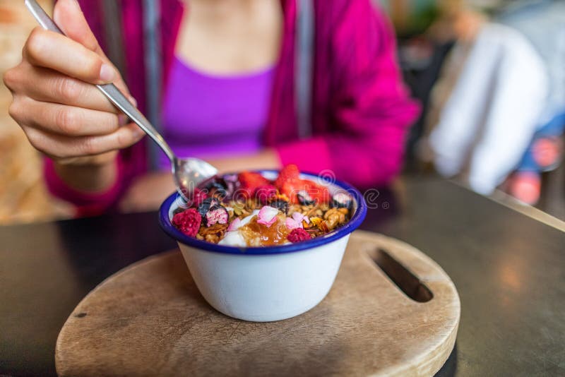 Acai bowl woman eating morning breakfast at cafe. Closeup of fruit smoothie healthy diet for weight loss with berries and oatmeal