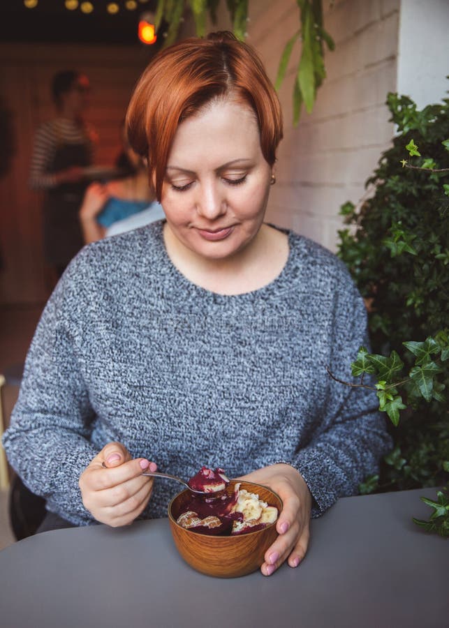 Acai smoothie, granola, seeds, fresh fruits in a wooden bowl in female hands on grey table. Eating healthy breakfast bowl stock images Acai smoothie, granola, seeds, fresh fruits in a wooden bowl in female hands on grey table. Eating healthy breakfast bowl stock images