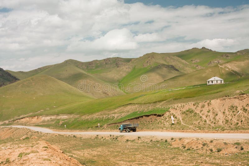 Acarree la conducción en una carretera nacional polvorienta en las montañas en un día soleado fotos de archivo Acarree la conducción en una carretera nacional polvorienta en las montañas en un día soleado fotos de archivo