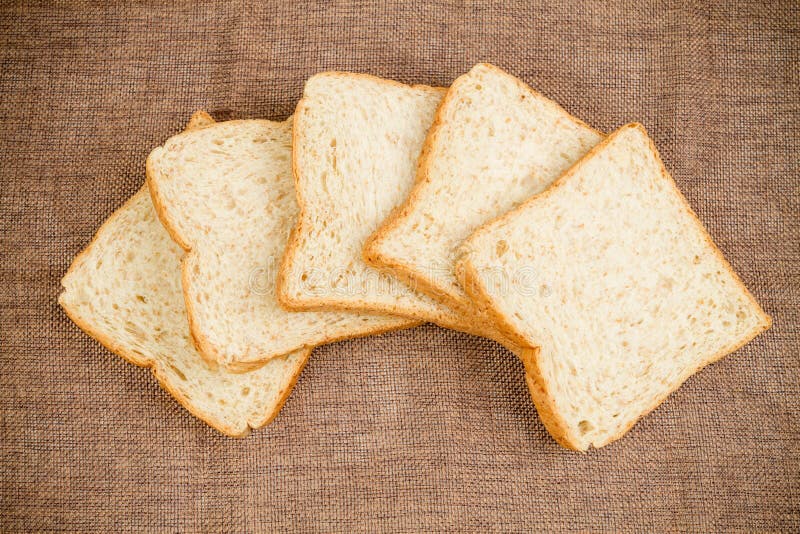Accatasti la fetta di pane integrale sul calicò di marrone scuro fotografia stock Accatasti la fetta di pane integrale sul calicò di marrone scuro fotografia stock