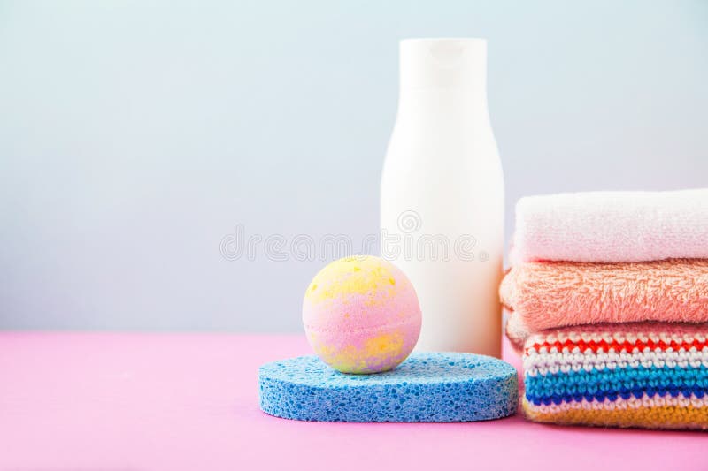 Accesorios del cuarto de baño - toallas y champúes, espuma del baño, crema en una luz, fondo azul y rosado brillante el concepto fotos de archivo libres de regalías Accesorios del cuarto de baño - toallas y champúes, espuma del baño, crema en una luz, fondo azul y rosado brillante el concepto fotos de archivo libres de regalías