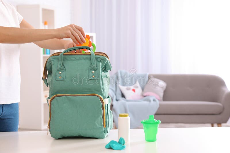 Accessoires de emballage de bébé de femme dans le sac à dos de maternité sur la table à l'intérieur photo libre de droits