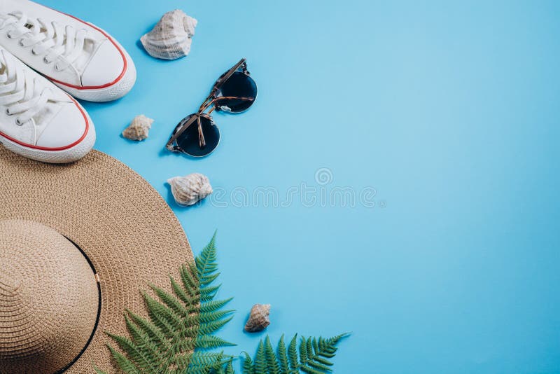 Accessoires étendus plats de voyageur sur le fond bleu avec les branches, les chaussures, le chapeau et le coquillage tropicaux d photo libre de droits Accessoires étendus plats de voyageur sur le fond bleu avec les branches, les chaussures, le chapeau et le coquillage tropicaux d photo libre de droits
