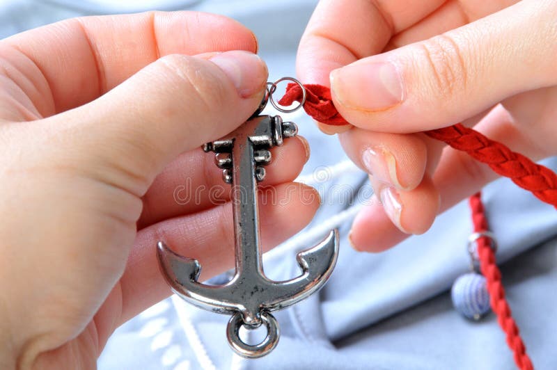 Accessories for Needlework. Hands with a Red Cord and Decoration