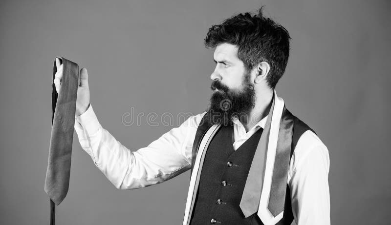 Accessory preserving the professional business look. Bearded man choosing menswear accessory. Businessman looking at luxury necktie accessory. Brutal caucasian man holding fashion accessory.