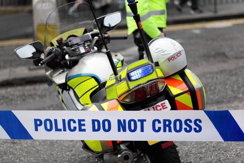 Policeman and police motorcycle behind cordon tape at an accident or crime scene